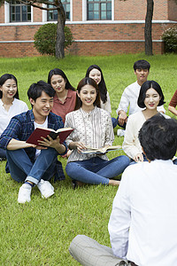 户外草坪上拿着书本的大学生图片