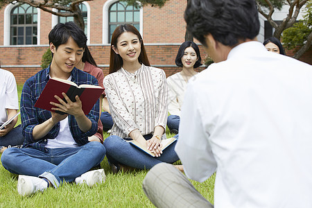 校园草坪上拿着书本的大学生图片