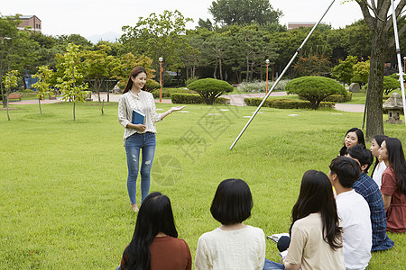 站在草坪上拿着书本的年轻女大学生图片