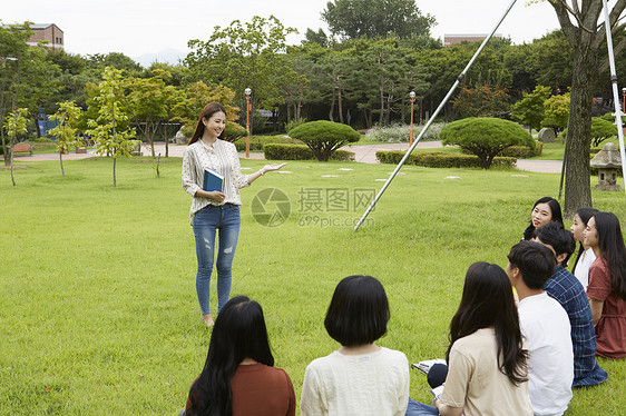 站在草坪上拿着书本的年轻女大学生图片