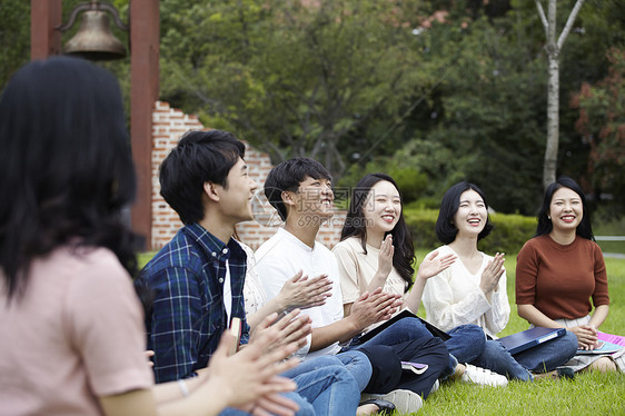 草坪上鼓掌开心的大学生图片