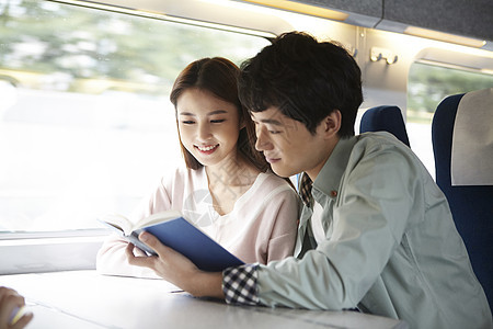 火车上看着书开心的年轻夫妇图片
