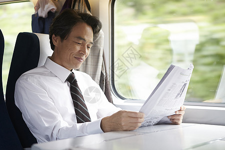 火车上看报纸微笑的成年男性图片