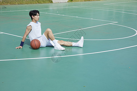 男青年坐在篮球场上图片