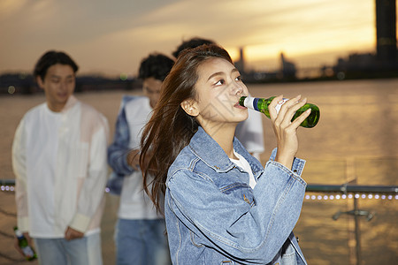 快乐的青年男女江边夜晚聚会喝酒图片素材