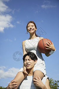 手拿篮球的女生坐在男生的肩头图片