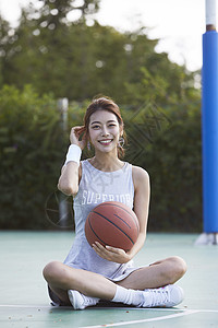 坐在球场抱着篮球的年轻女孩图片