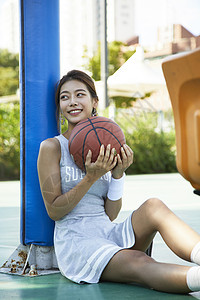 坐在球场抱着篮球的年轻女孩图片