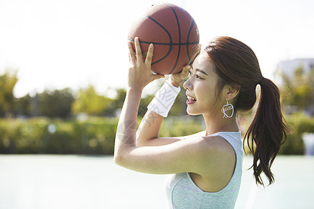 抱着篮球投篮的年轻女孩图片