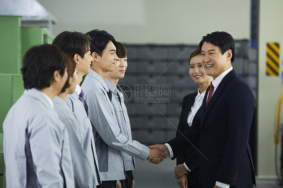 商务男士和工厂技术工人握手合作图片