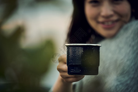 坐在户外手拿杯子喝咖啡的女性图片