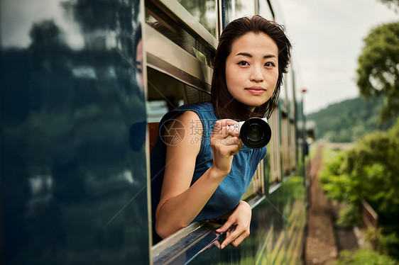 围栏二十多岁摄影女郎从车窗采取的女背包徒步旅行者图片