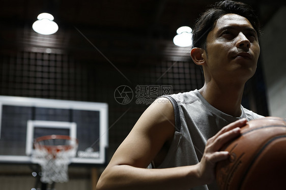 年轻男性在室内篮球场打球图片