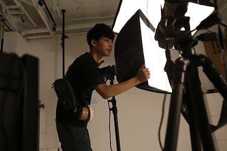 摄影棚调整打光灯的摄影助理图片素材