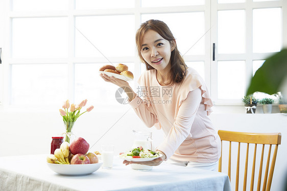 拿着一盘面包开心的年轻女性图片