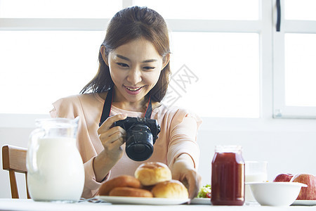 年轻女性微笑的拿着相机拍食物图片图片