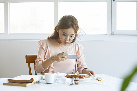 给美食拍照的年轻女子图片