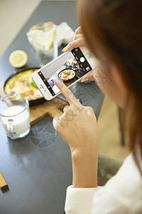 拿着手机拍食物照片的年轻女子特写图片