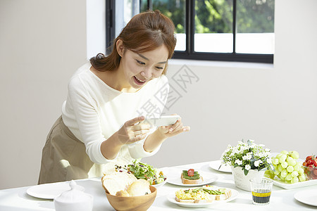 手机拍餐桌食物的女性图片