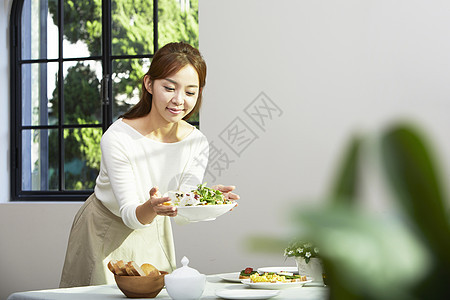 厨房餐桌上摆放餐具的成年女性图片