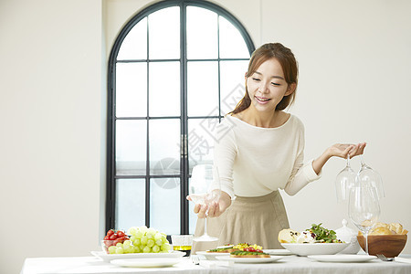 餐桌上摆放玻璃酒杯的成年女子图片