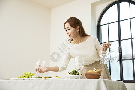 餐桌上摆放餐具的女青年图片