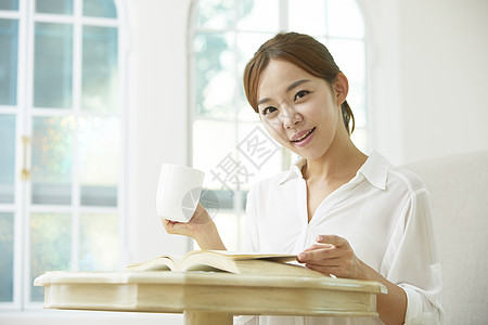 居家阅读喝咖啡的女青年高清图片