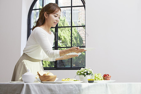 餐桌上摆放餐具的成年女子图片