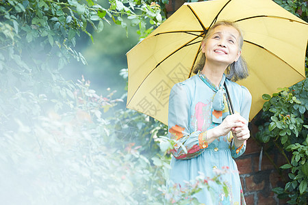 自然欣赏拿着一把伞的老年妇女在庭院里图片