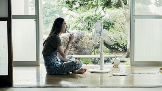 夏天坐着在家吹风扇吃冰棍的妇女图片