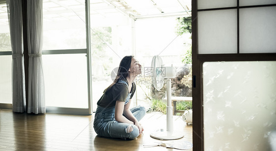 在家坐着吹风扇的妇女图片