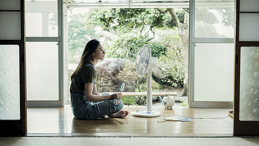 在房间里吹电风扇解暑的女孩图片