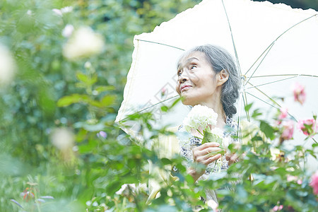 打着伞庭院里散步的老年女性图片