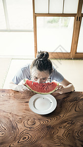 居家大口吃着西瓜的女性背景图片