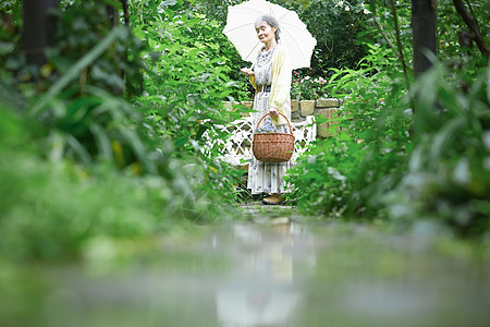 打开雨伞自然50多岁拿着遮阳伞的资深妇女在庭院里图片