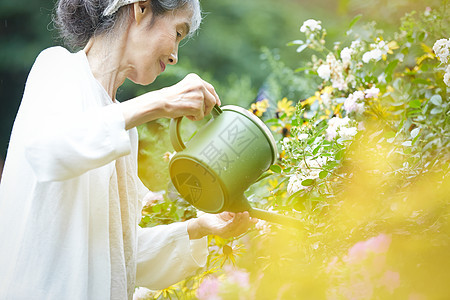 户外庭院拿着水壶浇水的妇女图片