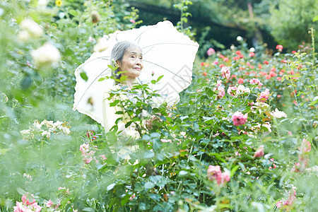 庭院里打着遮阳伞的老妇人图片