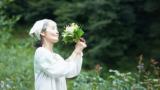 庭院里拿着花束的老年女性图片