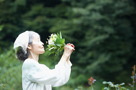 闭眼闻着鲜花的女性图片