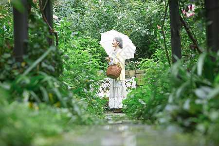 庭院里打着遮阳伞的老年女性图片