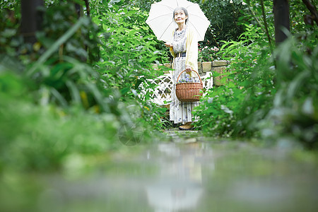 在庭院里撑着伞的老年女性图片