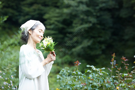 花园里捧着花束的老年女性图片