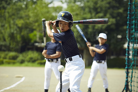 敲击头盔小学男孩棒球男孩实践的打击画象图片