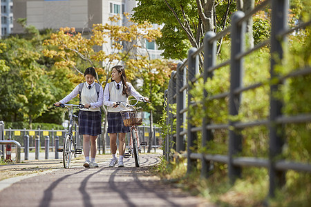 高中生推自行车行走图片