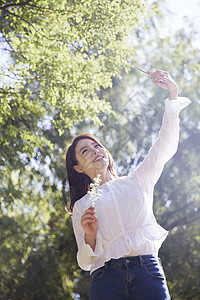 公园里拿着手机自拍的年轻女性图片