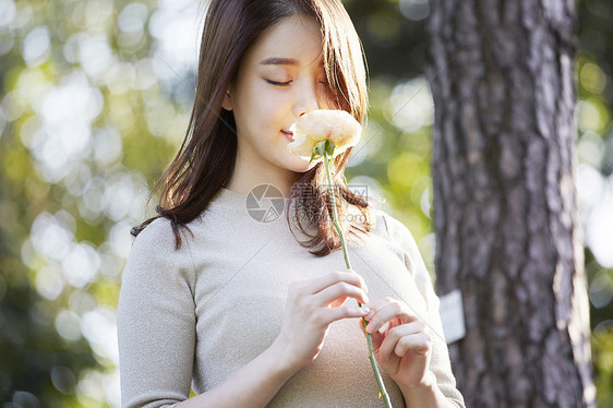 低头嗅闻花朵的年轻女性图片