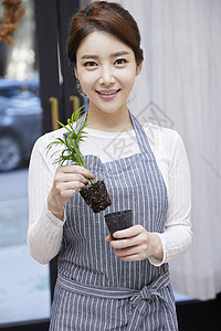 拿着植物微笑的年轻女子图片