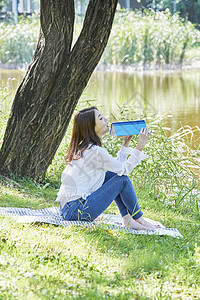 户外草坪上阅读的年轻女子图片