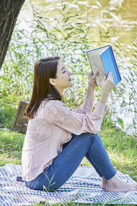 公园草坪上阅读的年轻女子图片