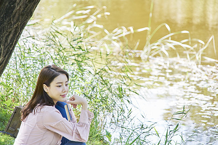 小河边阅读的女青年图片